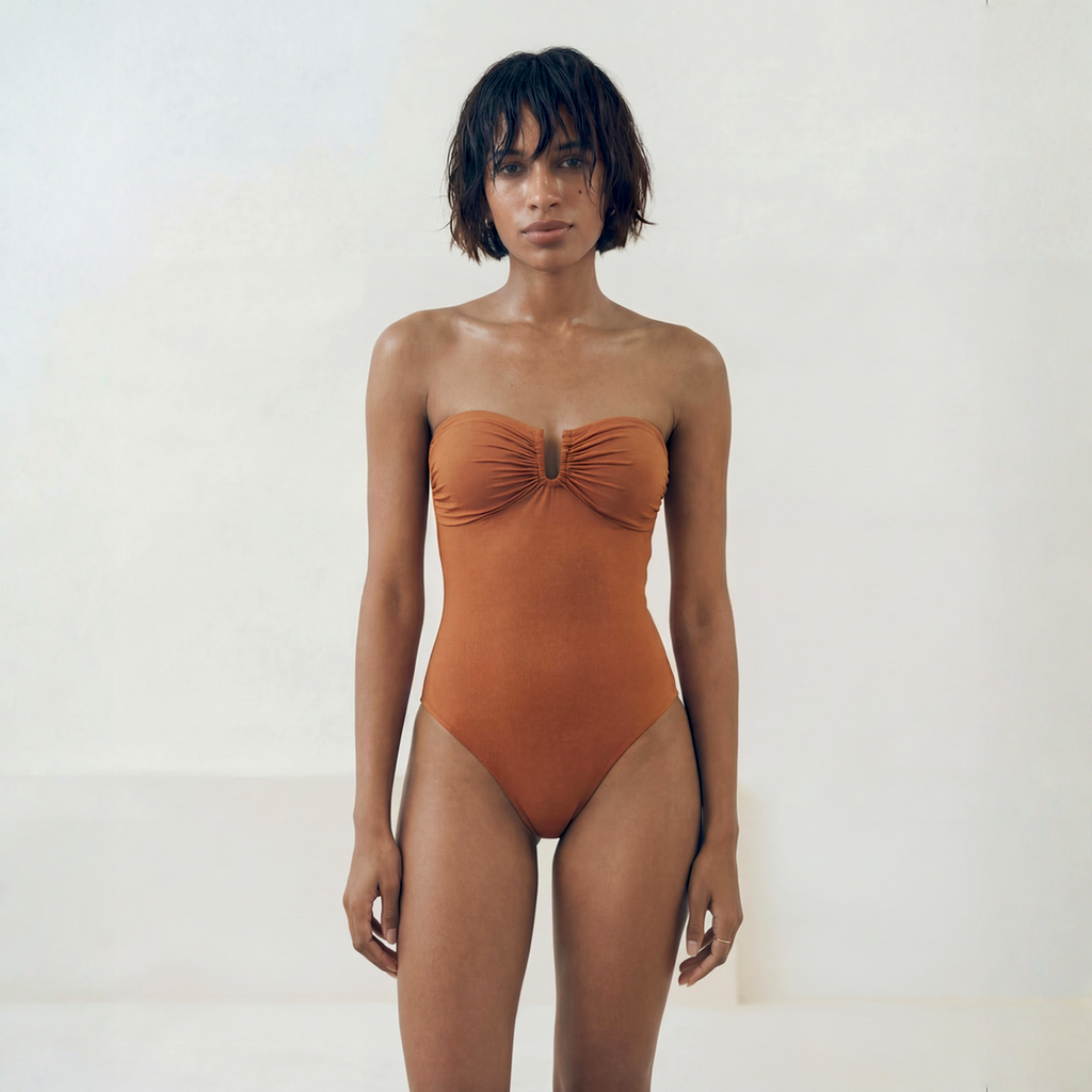 Woman wearing a rust-colored strapless swimsuit against a white background