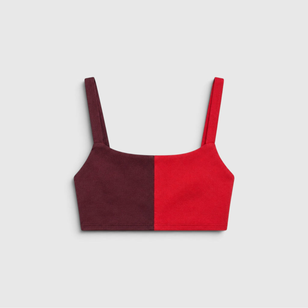 A color-blocked crop top with a square neckline and thin shoulder straps, featuring a split design of deep burgundy on the left and bright red on the right, shown against a light gray background.